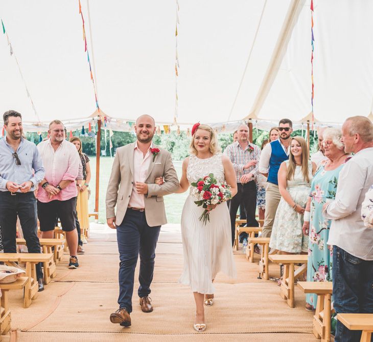 Bride and groom walking down the aisle together wearing midi wedding skirt with bunting decoration