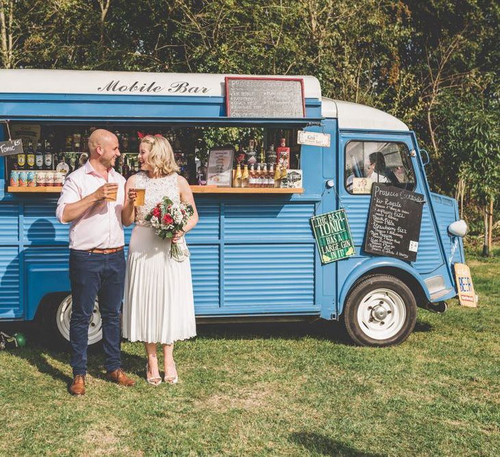 Bride wearing midi wedding skirt and groom enjoying the drinks truck at fun outdoor reception