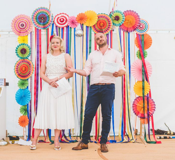 Bride and grooms first speech with midi wedding skirt and bright ribbon decor with colourful paper fans