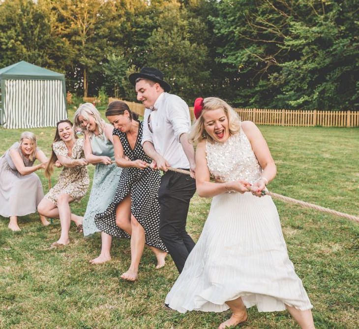 Tug of war wedding games with midi wedding skirt at this village fete themed celebration