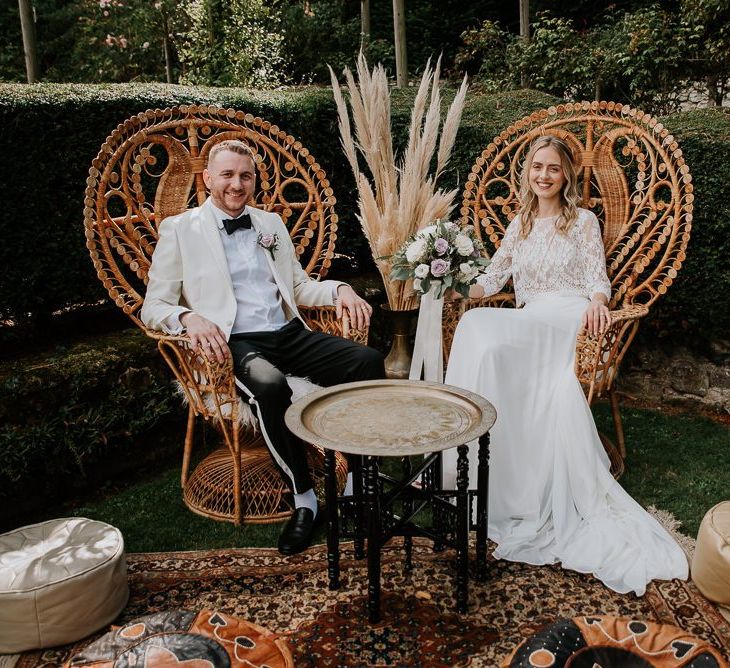 Bride and Groom Sitting in Chill Out Area with Peacock Chairs, Moroccan Rugs and Poufs