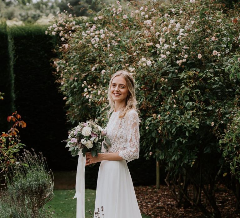 Bride in Wendy Makin Bridal Separates Holding a White and Purple Rose Wedding Bouquet Tied in Ribbons