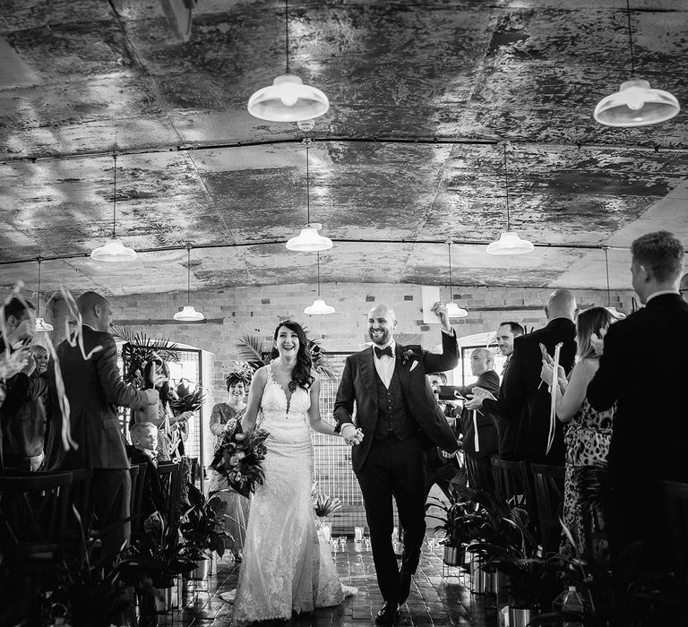 Bride in Martina Liana Lace Wedding Dress and Groom in Tom Ford Suit Walking Up The Aisle After Being Just Married