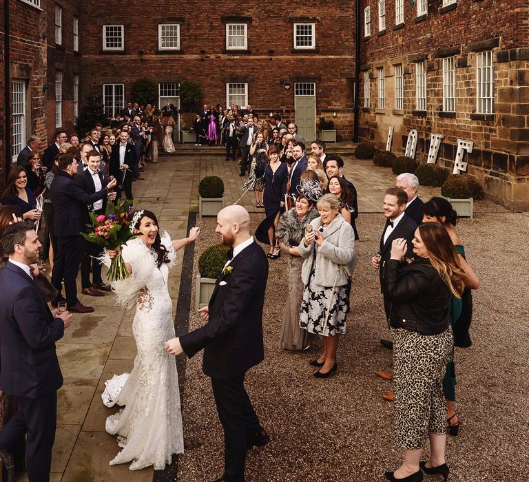 Bride in Martina Liana Wedding Dress &amp; Ostrich Feather Cover-up and  Groom in Tom Ford Suit Outside The West Mill Wedding Venue