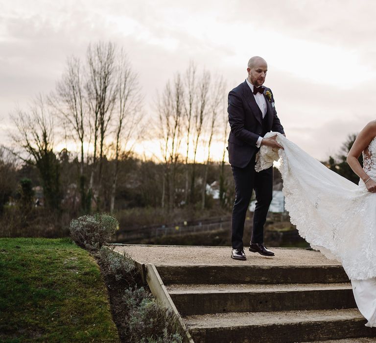 Groom in Tom Ford Suit Holding Up His Brides Lace Martina Liana Wedding Dress Train