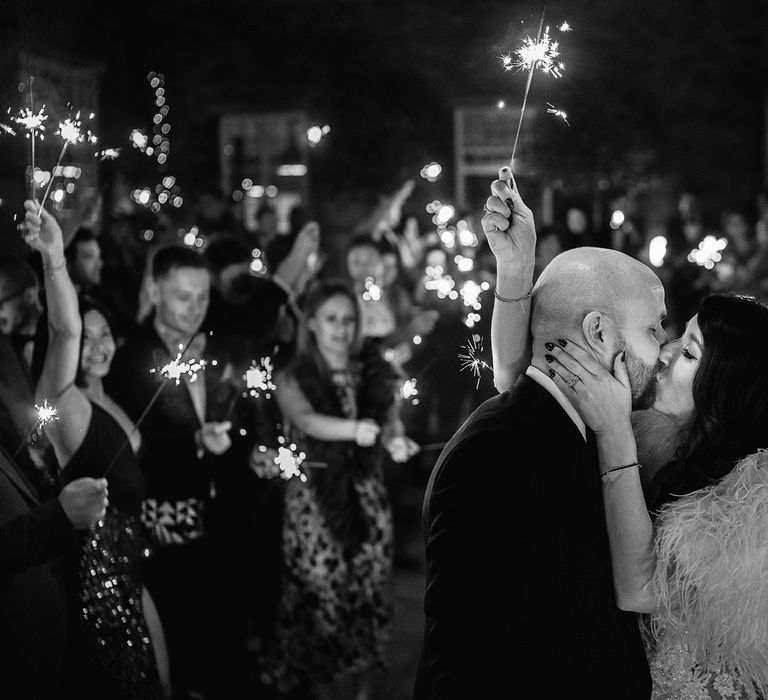 Bride in Martina Liana Wedding Dress &amp; Ostrich Feather Cover-up and Groom in Tom Ford Suit Kissing During Sparkler Moment