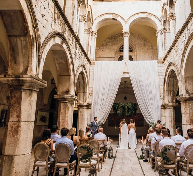 High low wedding dress and bespoke bridal cape for same-sex couple