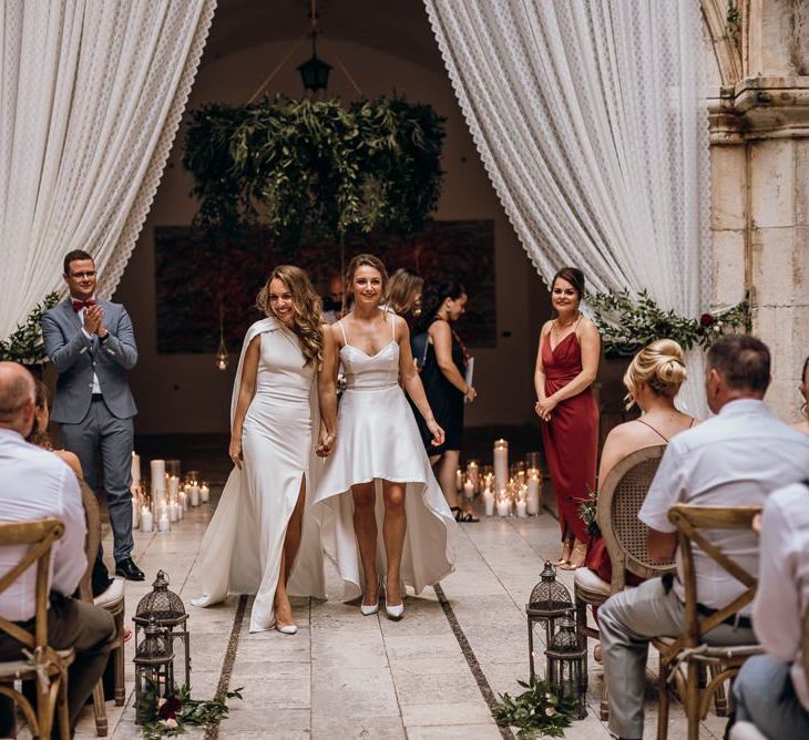 Bride in high low wedding dress walks down the aisle with her new wife