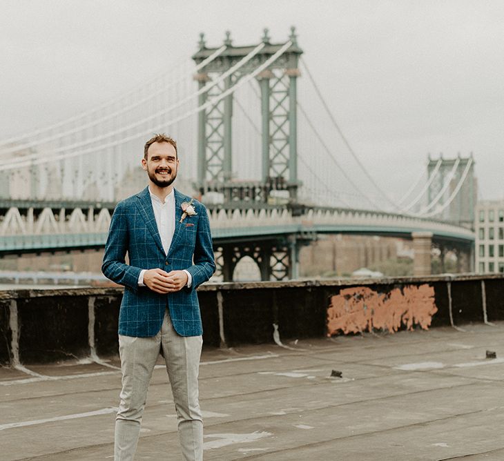 Groom waiting to see his bride for first look on rooftop building with Manhattan skyline