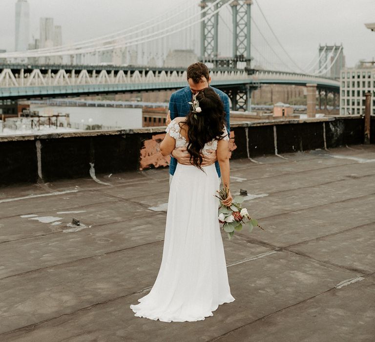 Bride and Groom embrace for first look moment on rooftop building with Manhattan skyline