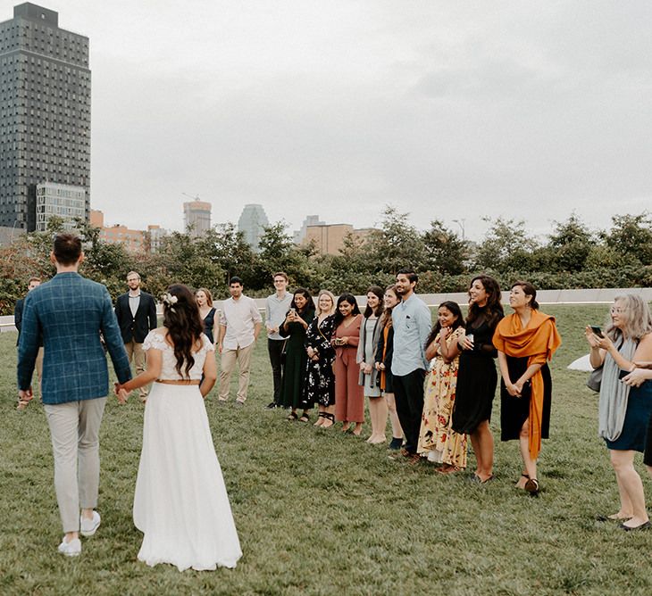 Bride and groom arriving at small ceremony with a semi circle of closes friends and family and NYC skyline backdrop