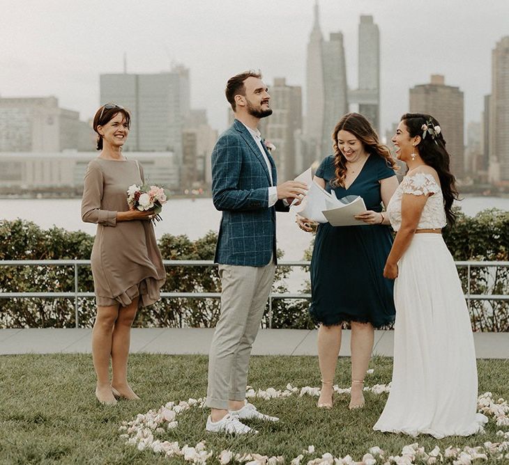 Bride and groom tie the knot at a park overlooking the East River and the NYC skyline  with groom in trainers