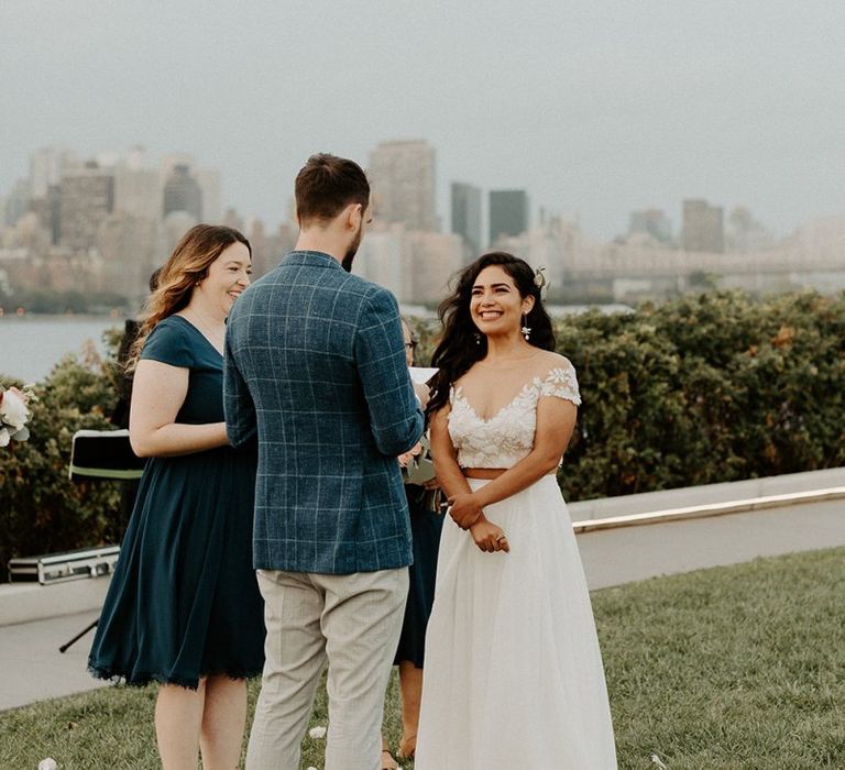 Bride and groom tie the knot at a park overlooking the East River and the NYC skyline with Groom in blazer