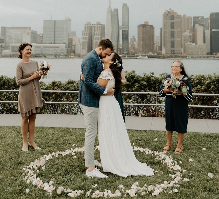 Bride and grooms first kiss at a park overlooking the East River and the NYC skyline