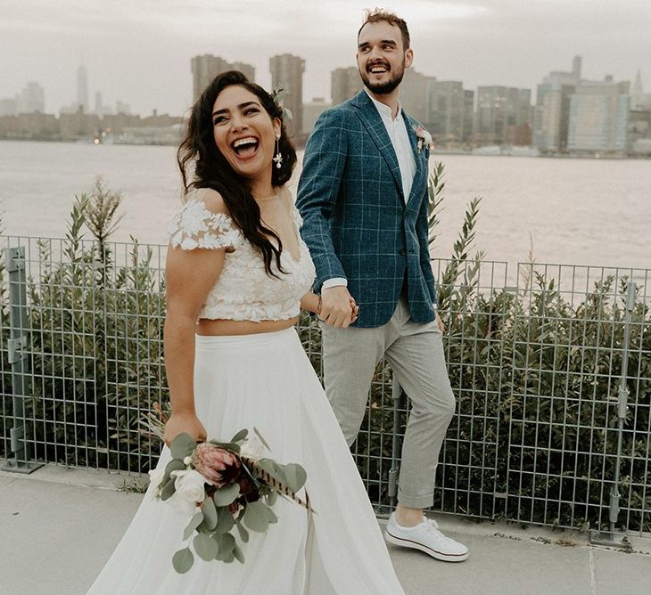 Bride wearing bridal separates with a king protea bouquet and groom in white trainers