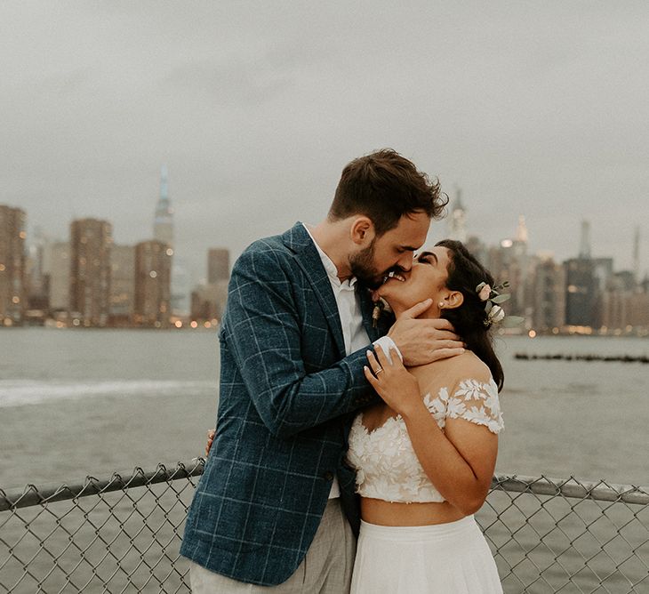 Bride and groom embrace with the NYC skyline backdrop