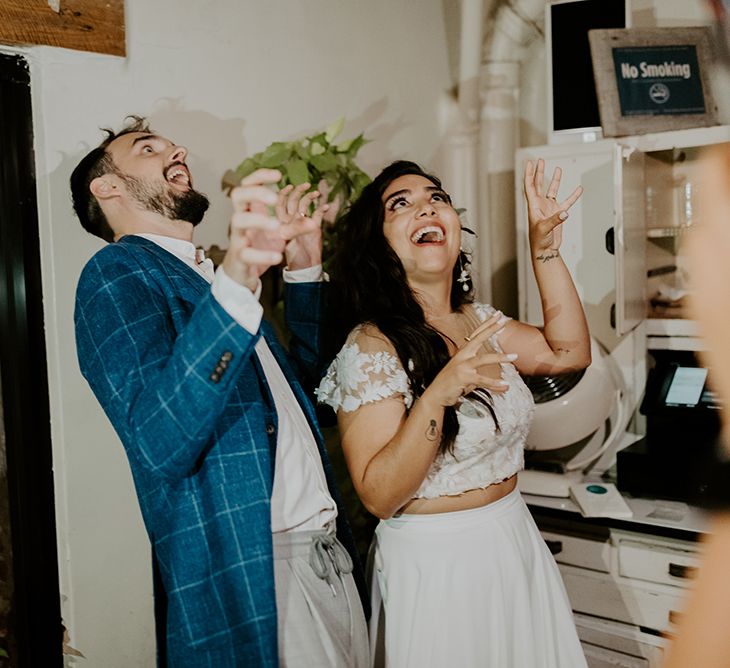 Bride and groom at Brooklyn elopement with semi naked wedding cake and a dinosaur cake topper