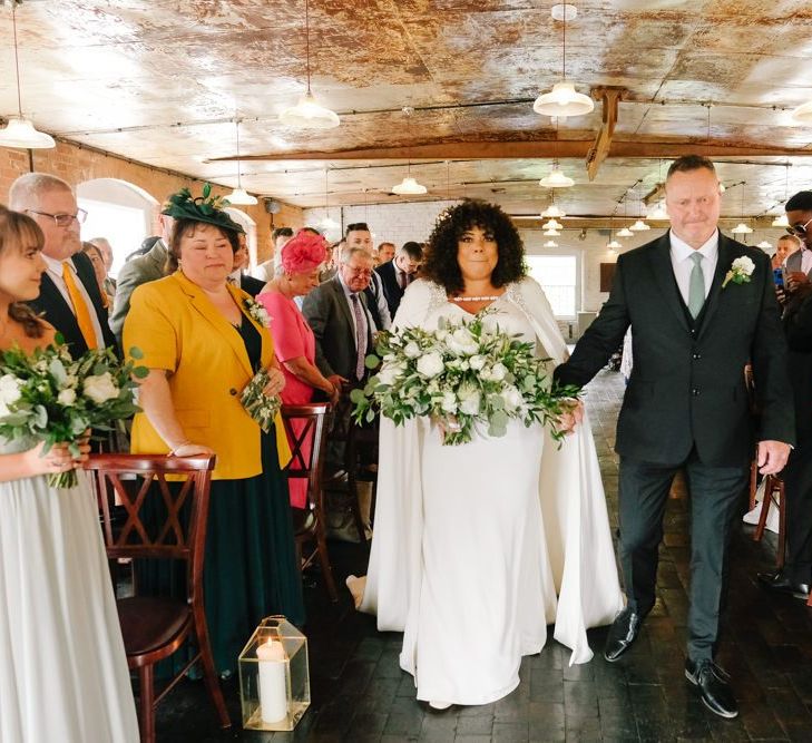 Bride in bridal cape walks down the aisle