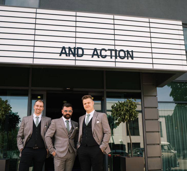 Groom and groomsmen outside venue with customised neon sign