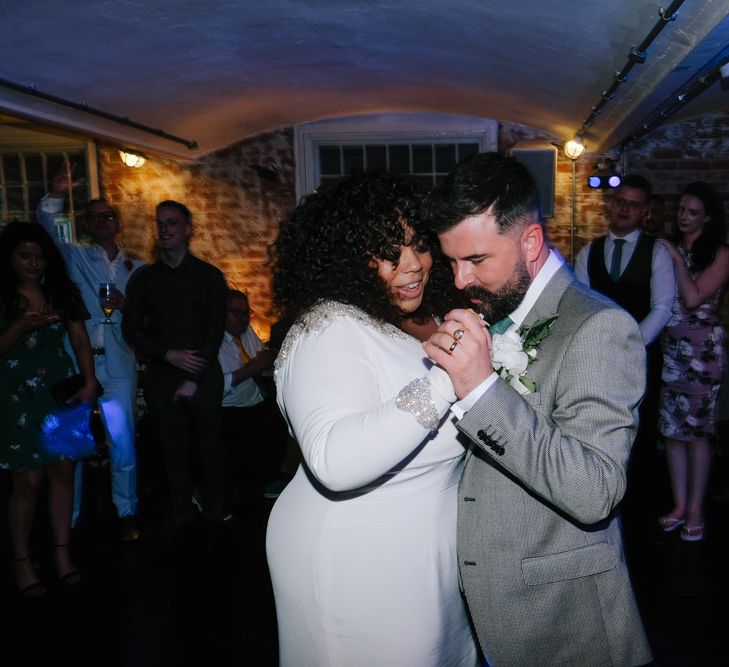 Bride in long sleeved dress for first dance at industrial wedding with customised neon sign