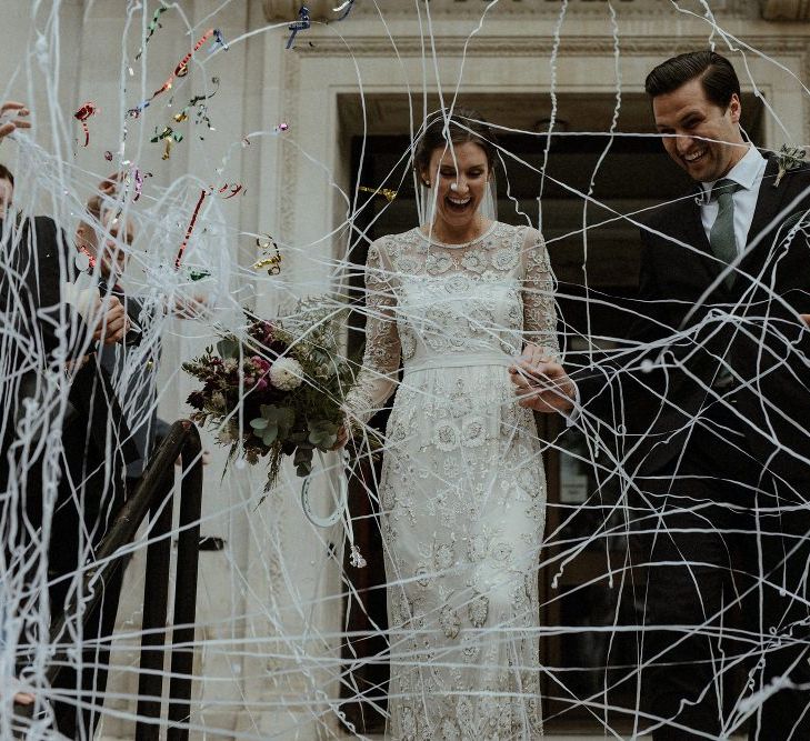 Just Married | Bride in Beaded Needle &amp; Thread Wedding Dress with Long Sleeves | Groom in Marks &amp; Spencer Suit with Olive Tie | Britten Veil | Maroon and White Bridal Bouquet with Green Foliage | Islington Town Hall | Beaded Needle &amp; Thread Dress for Intimate Islington Wedding | Olivia &amp; Dan Photography