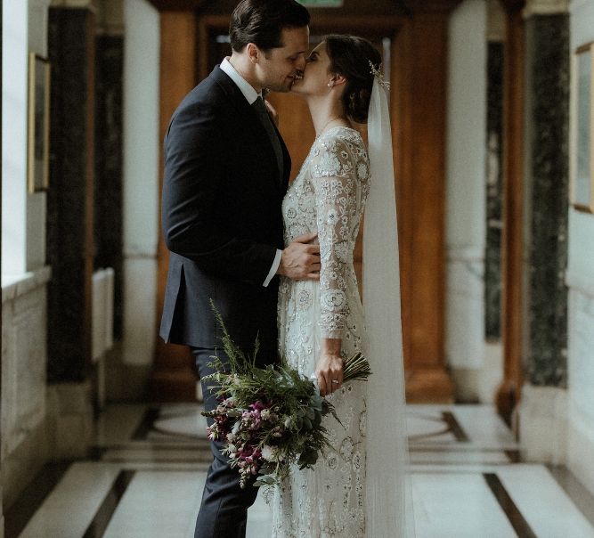 Bride in Beaded Needle &amp; Thread Wedding Dress with Long Sleeves | Groom in Marks &amp; Spencer Suit with Olive Tie | Britten Veil | Tania Maris Hairpiece | Maroon and White Bridal Bouquet with Green Foliage | Beaded Needle &amp; Thread Dress for Intimate Islington Wedding | Olivia &amp; Dan Photography