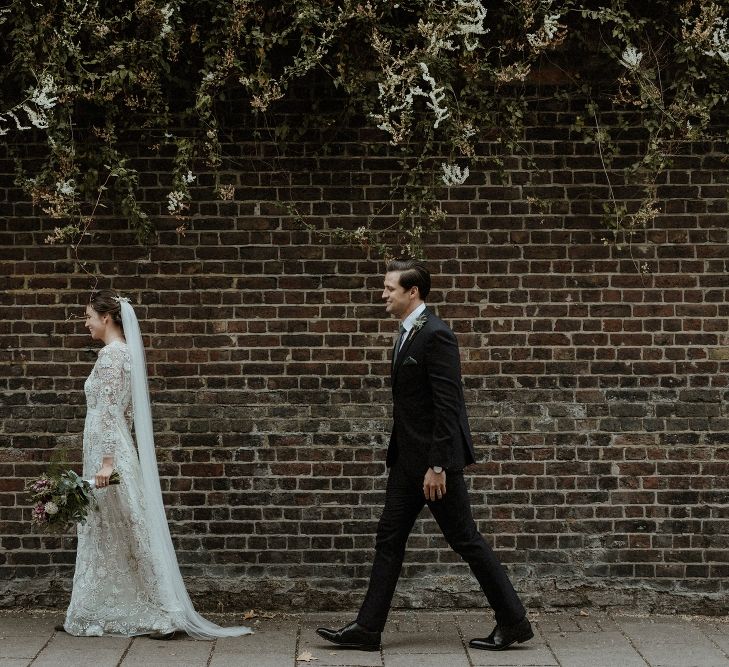 Bride in Beaded Needle &amp; Thread Wedding Dress with Long Sleeves | Groom in Marks &amp; Spencer Suit with Olive Tie | Britten Veil | Tania Maris Hairpiece | Olive Green Sergio Rossi Shoes | Maroon and White Bridal Bouquet with Green Foliage | Beaded Needle &amp; Thread Dress for Intimate Islington Wedding | Olivia &amp; Dan Photography