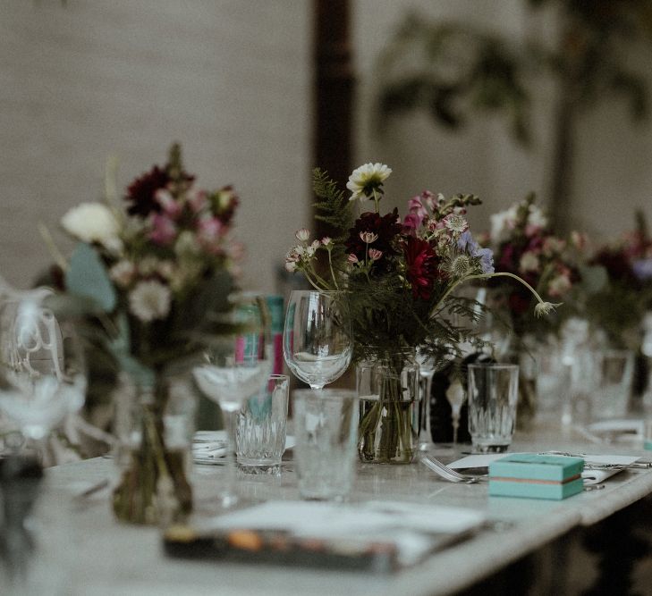 Wedding Reception Decor | Maroon and White Table Flowers with Thistles and Foliage in Mason Jars | Fortnum &amp; Mason Favours | Bourne &amp; Hollingsworth Buildings | Greenhouse Reception Venue | Beaded Needle &amp; Thread Dress for Intimate Islington Wedding | Olivia &amp; Dan Photography