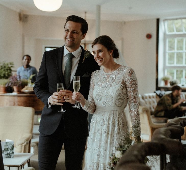 Wedding Reception | Champagne | Bride in Beaded Needle &amp; Thread Wedding Dress with Long Sleeves | Groom in Marks &amp; Spencer Suit with Olive Tie | Britten Veil | Maroon and White Bridal Bouquet with Green Foliage | Beaded Needle &amp; Thread Dress for Intimate Islington Wedding | Olivia &amp; Dan Photography