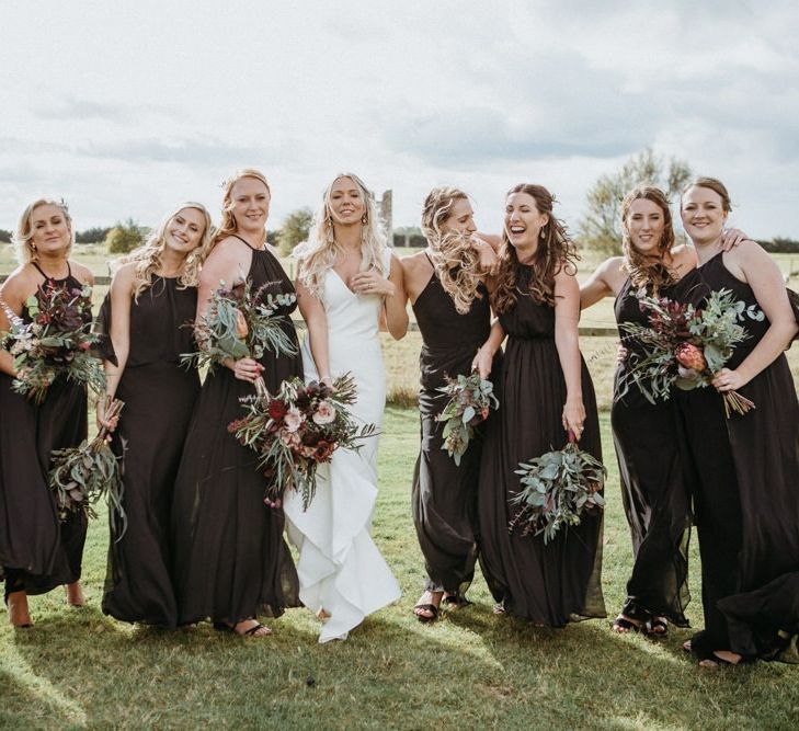 Black bridesmaid dresses alongside minimalist wedding dress