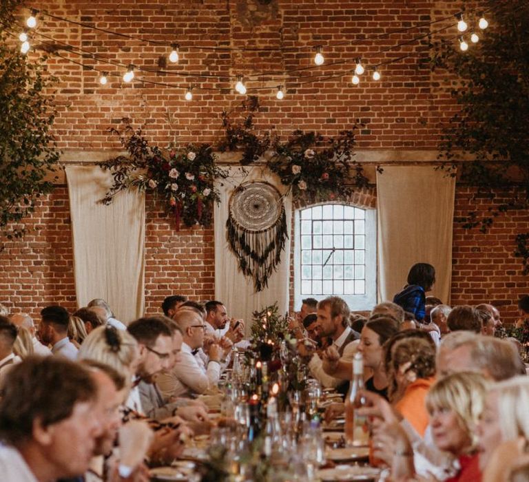 Wedding guests enjoy dinner and supermarket wedding cake beneath the festoon lighting