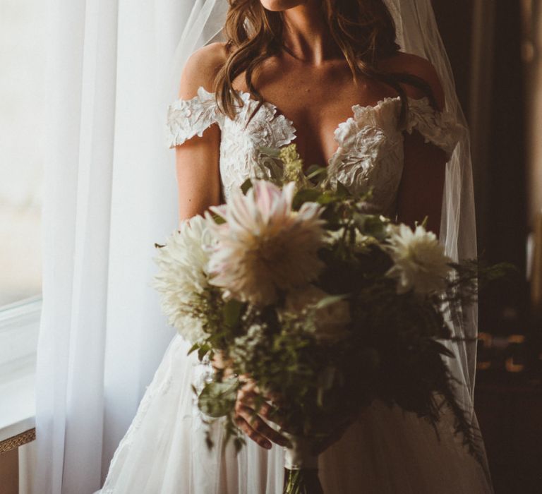 Bride wearing off the shoulder laced Martina Liana dress with veil and white foliage bouquet