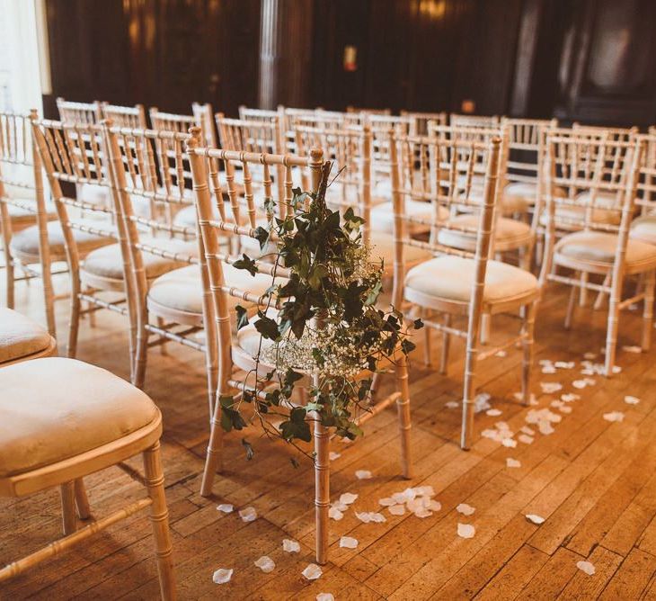 White floral chair back decor with scattered petals at London reception