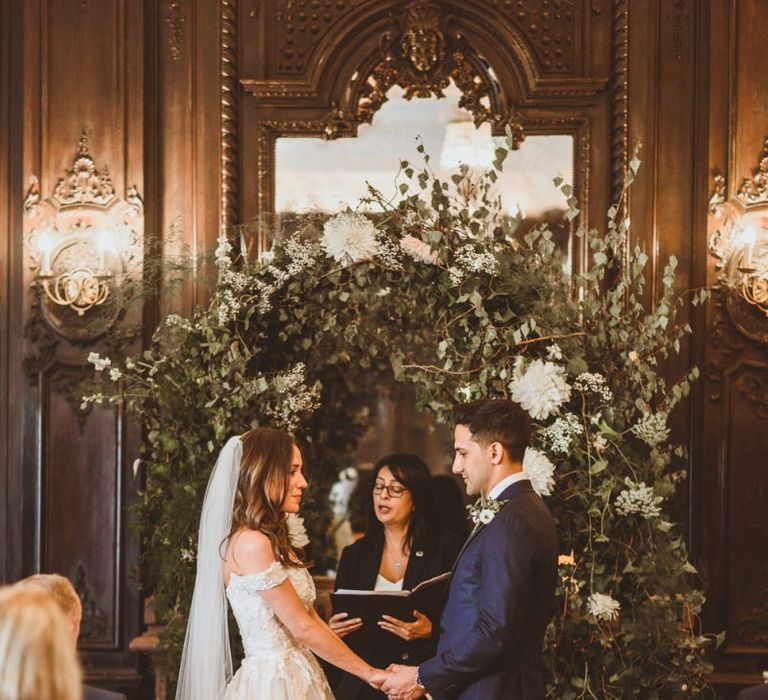 Bride and groom tie the knot at London ceremony with white foliage archway and pillar candles