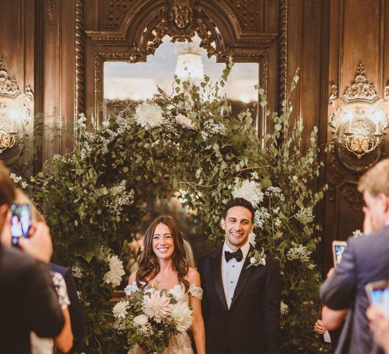 Husband and wife at London ceremony with white foliage decor