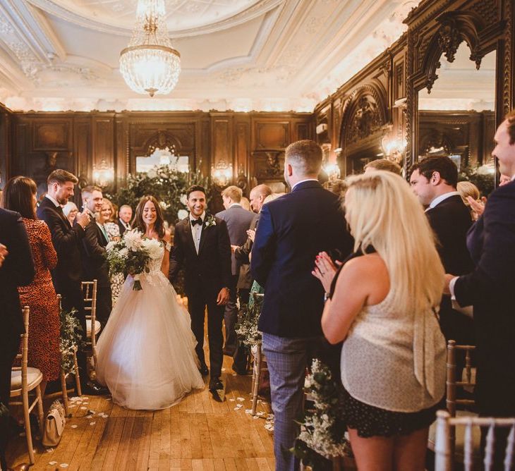 Husband and wife at London ceremony with white foliage styling and floral chair back decor