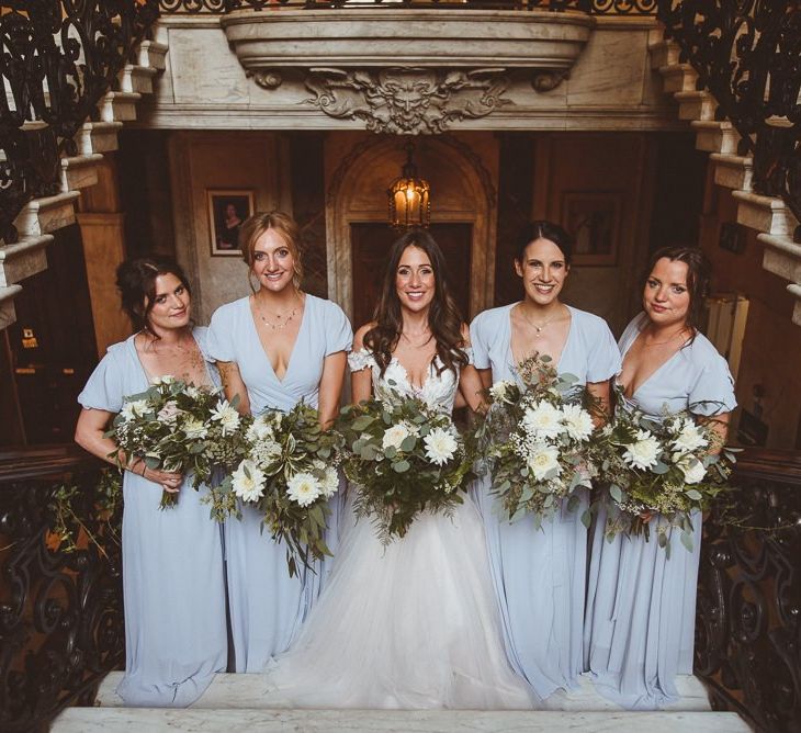 Bride wearing Martina Liana with her bridesmaids in pale blue dresses and white foliage bouquets