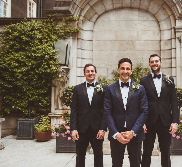 Groom and his groomsmen in black tie with white floral buttonholes