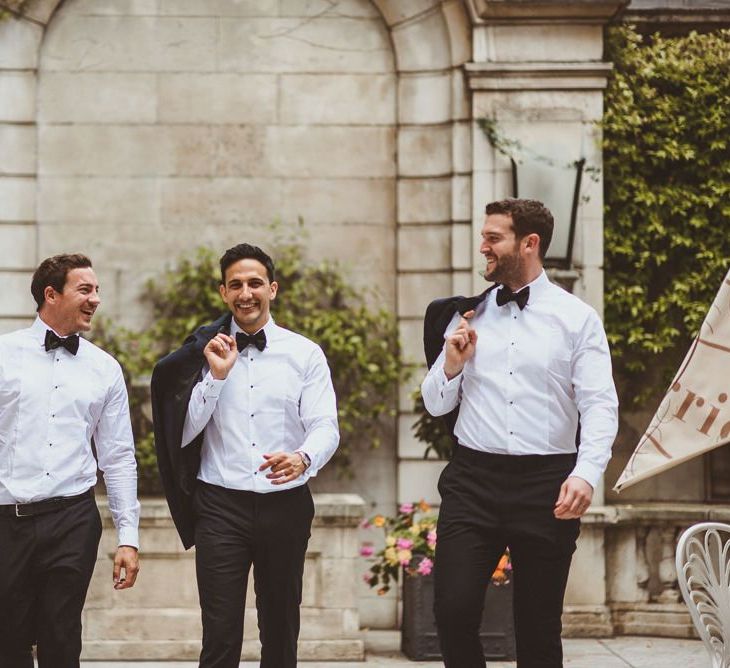 Groom and his groomsmen in black tie with white floral buttonholes