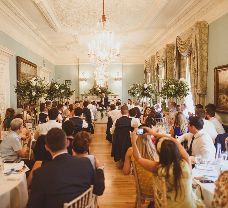 Guests celebrate the big day at beautiful London venue with tall floral centrepieces