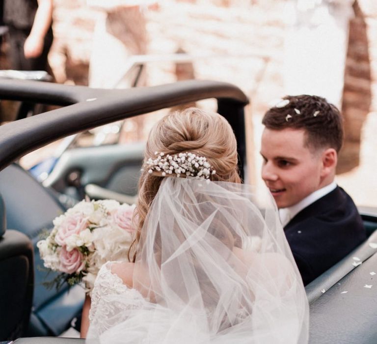 Bride Sitting in the Car with Fresh Gypsophila in the Hair and Wedding Veil