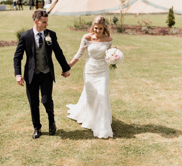 Bride in Lace Mori Lee Madeline Gardner Wedding Dress and Groom in Navy Suit with Grey Waistcoat Holding Hands