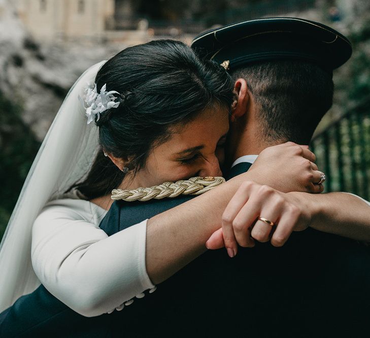 Bride hugs her uniform wearing groom