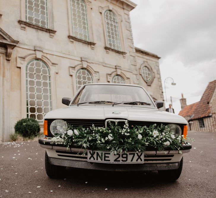 Vintage BMW Wedding Car with White and Green Wedding Flowers Decorating the Bumper