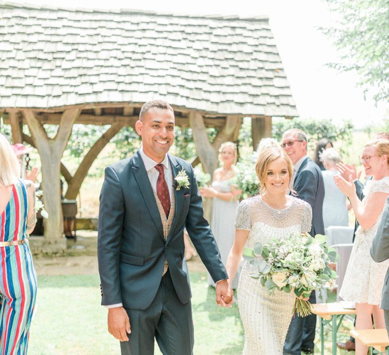 Bride in Beaded Wedding Dress and Groom in Dark Suit &amp; Check Waistcoat Walking Up The Aisle as Husband  and Wife