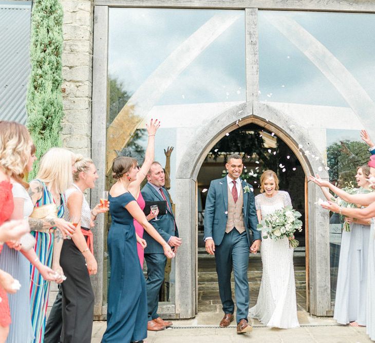 Confetti Moment with Bride in Beaded Wedding Dress and Groom in Dark Suit &amp; Check Waistcoat