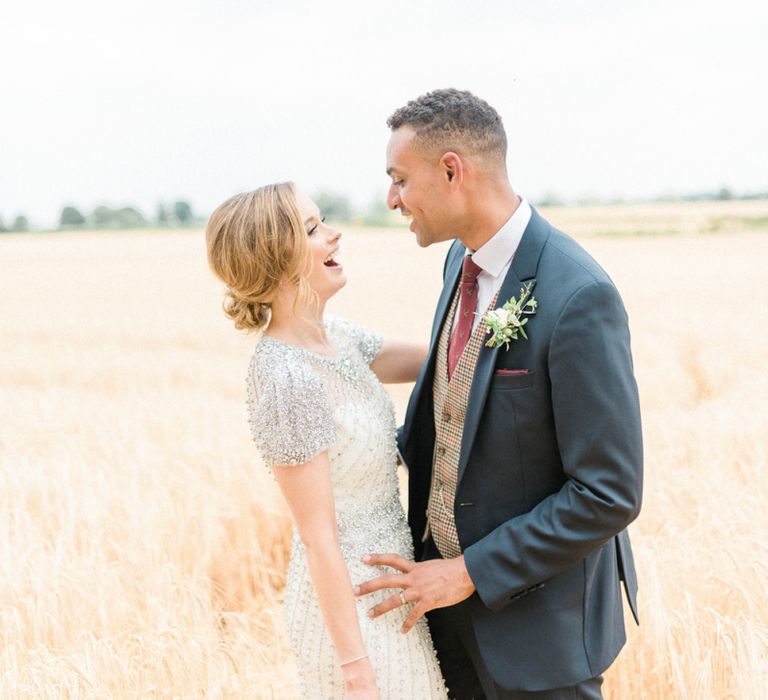 Laughing Bride in Beaded Wedding Dress and Groom in Dark Suit &amp; Check Waistcoat