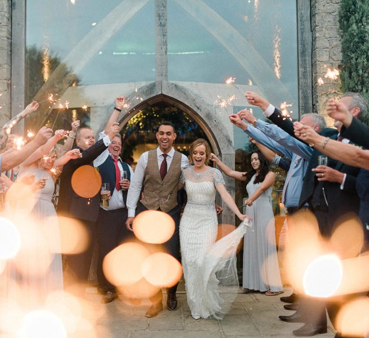 Sparkler Exit Bride in Beaded Wedding Dress and Groom in Dark Suit &amp; Check Waistcoat