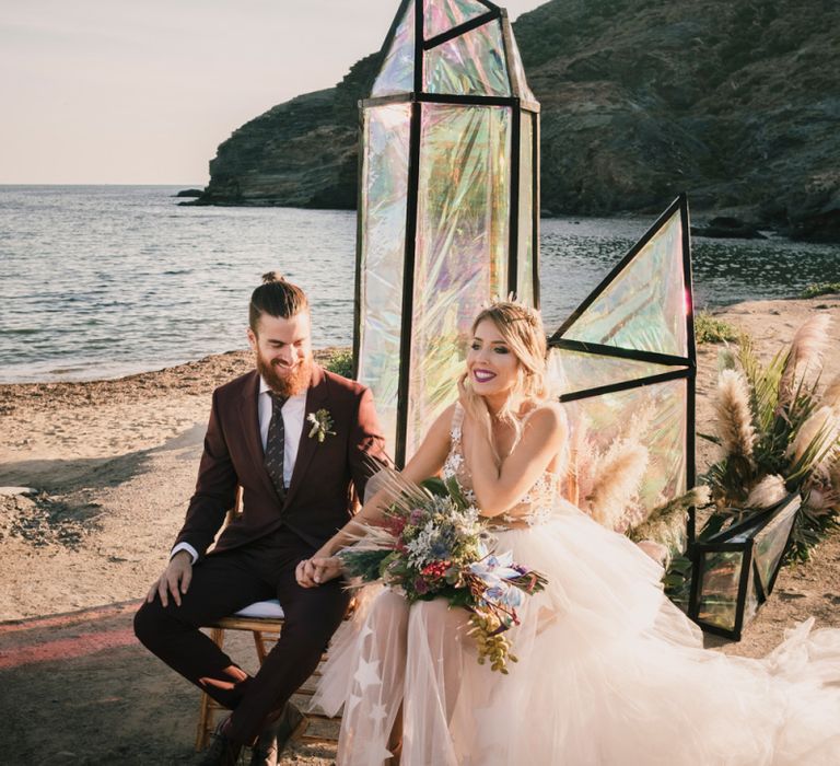 Bride and groom sat on beach