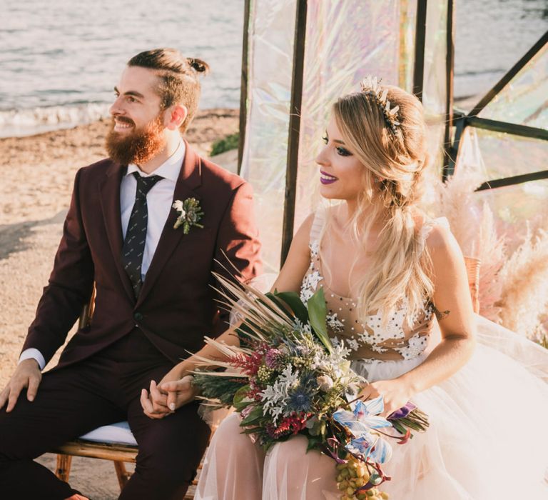 Bride and groom sat on beach